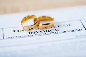 A Divorcee Decree With Two Gold Wedding Rings Resting On Top.