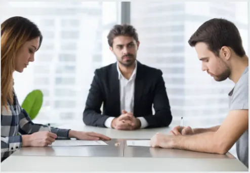 A Couple Looking Over An Agreement With An Attorney.