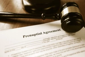 A Prenuptial Agreement Document And A Gavel On A Wooden Desk.