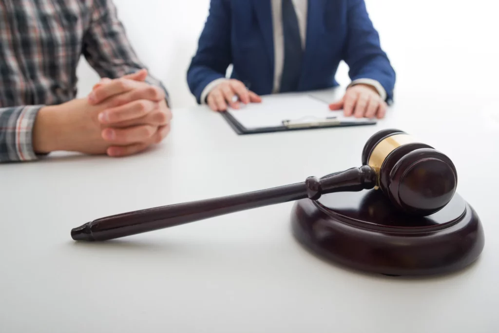 Lawyer And A Client Sitting At A Conference Table With A Wooden Gavel.